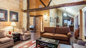 A cozy log cabin interior with a living room featuring a brown sofa, a coffee table, and a fireplace. - Shenandoah Crossing Resort with acres of wilderness (Gordonsville)
