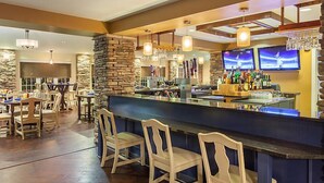 A bar area with a stone accent wall, wooden bar counter, and multiple hanging light fixtures. - Shenandoah Crossing Resort with acres of wilderness (Gordonsville)