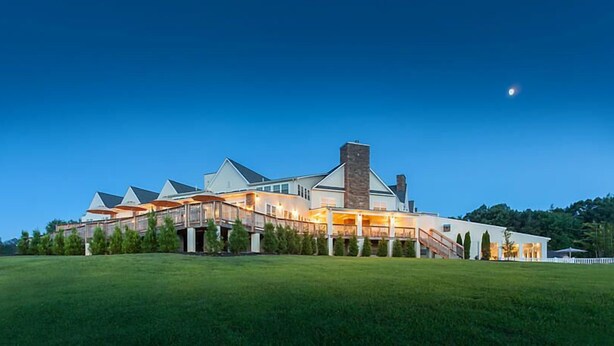 A large, modern house with multiple levels and a prominent chimney, surrounded by a well-maintained lawn. - Shenandoah Crossing Resort with acres of wilderness (Gordonsville)