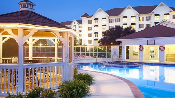 A swimming pool with a gazebo and lounge chairs, surrounded by a building with multiple balconies.