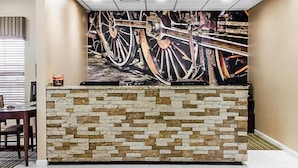 A reception desk with a stone facade and a large abstract painting above it.
