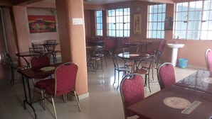A dining area with multiple tables and chairs, a sink, and a painting on the wall. - Sirlo Hotel (Thika)
