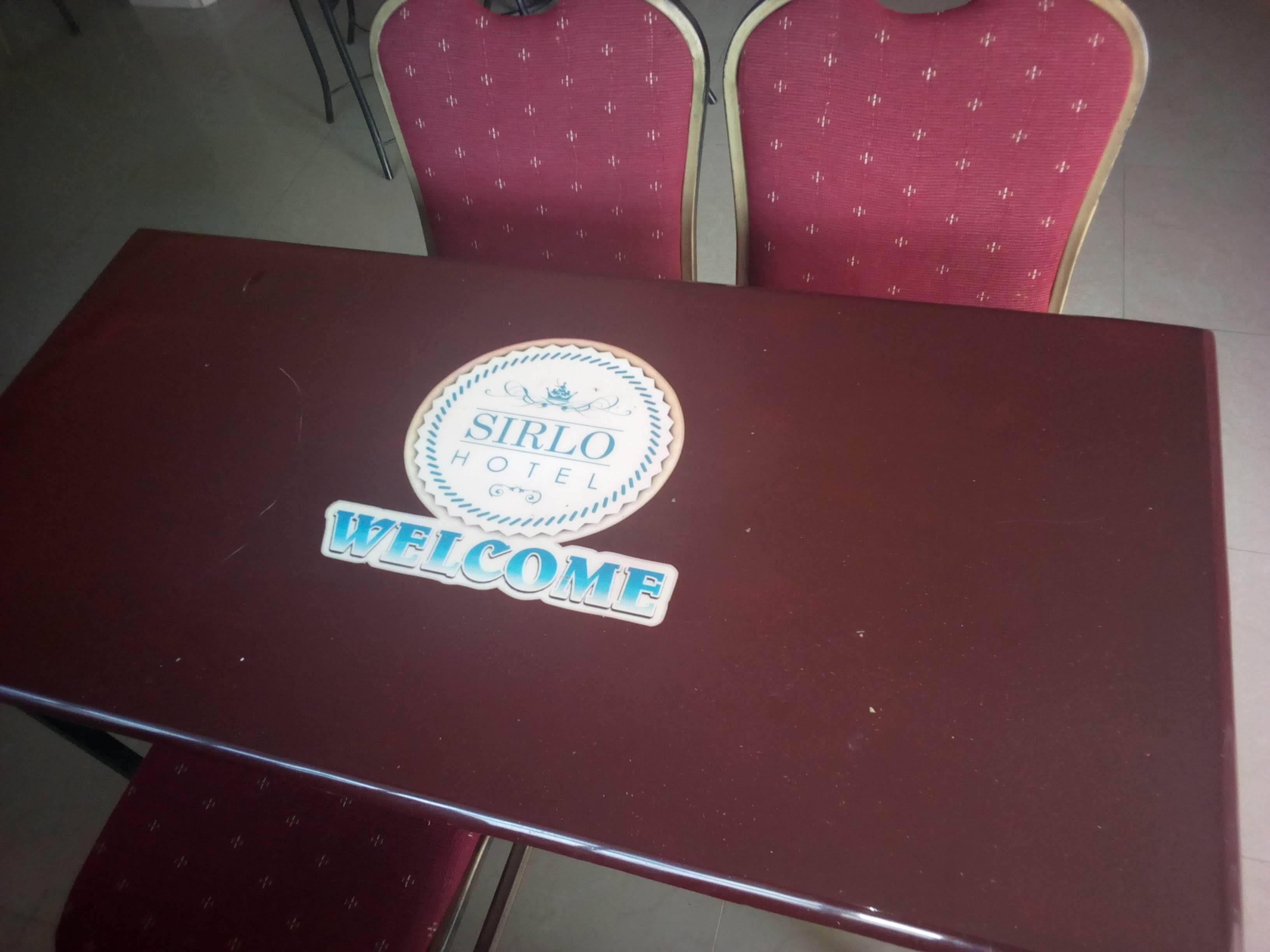 A table with a 'SIRLO HOTEL' sign and a 'WELCOME' sign.