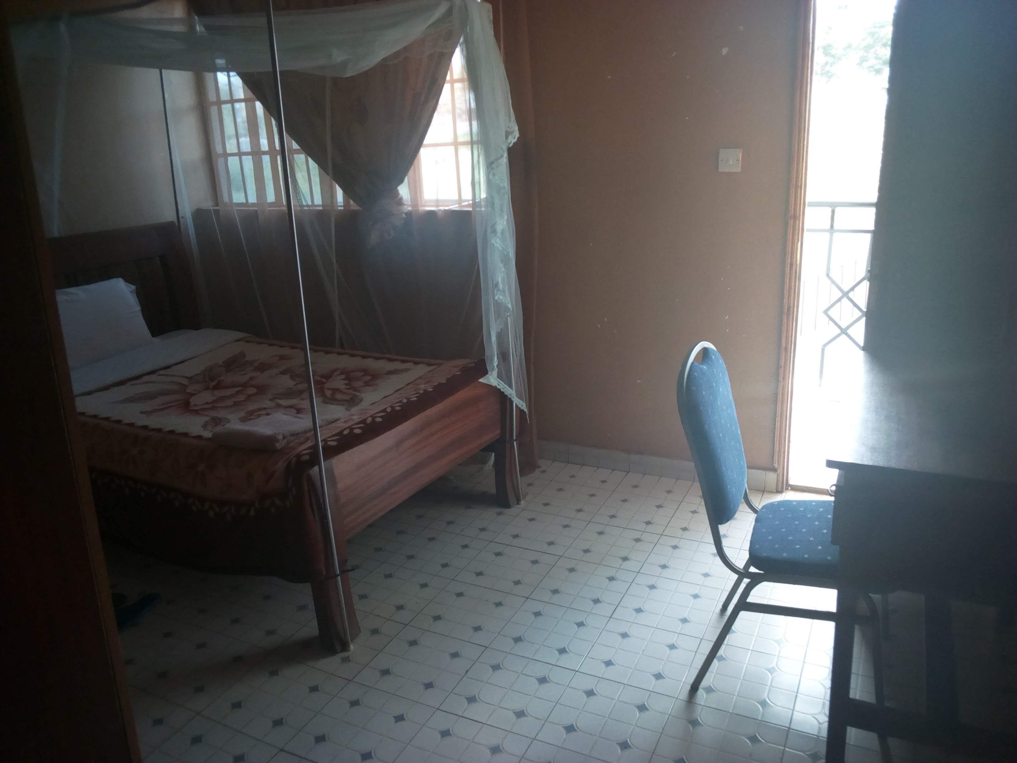 A room with a bed, a chair, and a window.