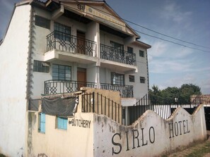 Un edificio de dos pisos con balcones y un cartel que indica que es el Sirlo Hotel.