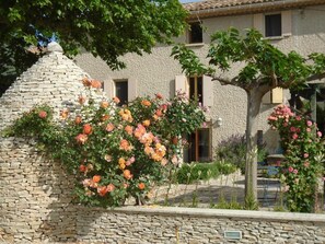 A stone building with a stone wall and a tree with pink flowers.