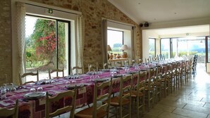 A long dining table set for a meal in a room with stone walls and large windows. - Le Moulin de Lavon (Gargas)