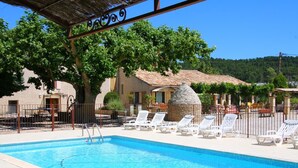 A swimming pool with lounge chairs and a stone structure. - Le Moulin de Lavon (Gargas)