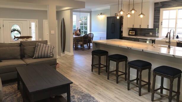 Een moderne keuken met een marmeren aanrecht, donkerhouten stoelen en hanglampen.