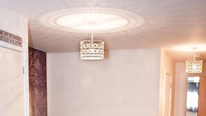 A bedroom with a bed, a wooden floor, a ceiling light fixture, and a door.