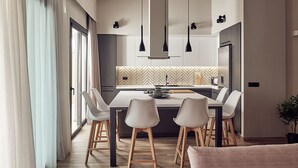 A modern kitchen with a central island, pendant lights, and a dining area with chairs. - Private pool Villa with sea view at 250 m from the sea/beach (zakynthos)