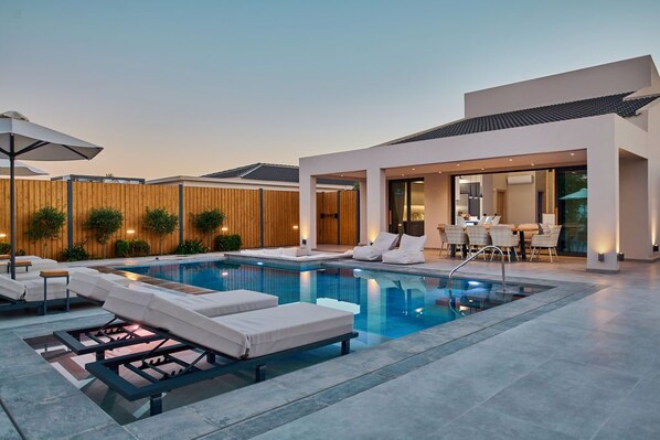 A modern outdoor pool area with lounge chairs and a dining area. - Private pool Villa with sea view at 250 m from the sea/beach (zakynthos)