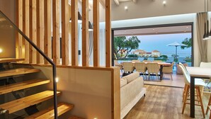 A modern interior with a wooden staircase, a sofa, and a dining area with a view of the sea. - Private pool Villa with sea view at 250 m from the sea/beach (zakynthos)