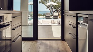 A modern kitchen with a sliding glass door leading to a balcony with a pool and lounge chairs. - Private pool Villa with sea view at 250 m from the sea/beach (zakynthos)
