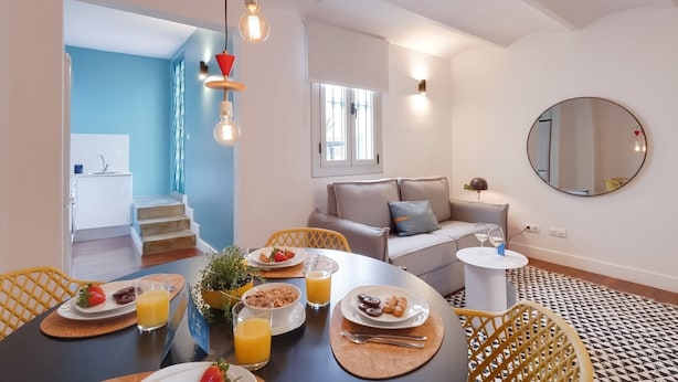 Un salon moderne avec un canapé, une table à manger où l’on prend le petit-déjeuner, et un grand miroir.