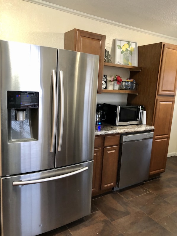 A kitchen with stainless steel appliances, wooden cabinets, and a countertop microwave.