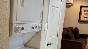 A laundry room with a white washer and dryer, a door leading to a living area with a brown couch. - Big Bend Getaway..... (Alpine)