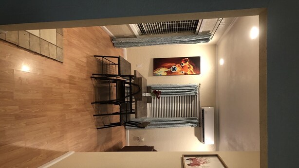A dining area with a wooden floor, a table with chairs, a radiator, and a painting on the wall. - Big Bend Getaway..... (Alpine)
