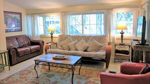 A living room with a brown leather sofa, a patterned sofa, a coffee table, and two lamps. - Angler Haus , Rustic Wundercove Cottage , Access to Shared Pool and River (New Braunfels)
