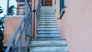 A staircase leading to a building entrance with a metal railing and a door with a window. - Sunshine apartment - terrace in Acquaseria (Acquaseria)