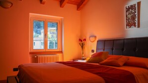 A bedroom with a bed, a window, a radiator, and a vase with flowers. - Sunshine apartment - terrace in Acquaseria (Acquaseria)