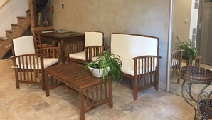 A wooden dining set with chairs and a table, a potted plant, and a staircase in the background.