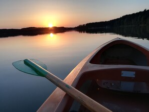 Ein Kanu mit Paddel auf einem stillen See bei Sonnenuntergang.