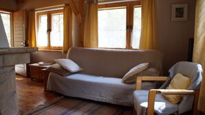 Une pièce confortable avec un canapé, un fauteuil, une petite table et une fenêtre avec des rideaux.