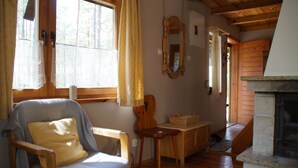 Une pièce chaleureuse avec une chaise en bois, une petite table, un miroir et une cheminée.