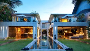 A modern two-story house with a central glass pool, outdoor seating, and a well-maintained lawn. - 5 Bedroom Holiday Villa in Seminyak with Private Pool, Bali Villa 2001 (Bali)