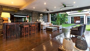 A spacious living area with a bar, seating, and a view of the outdoors. - 5 Bedroom Holiday Villa in Seminyak with Private Pool, Bali Villa 2001 (Bali)