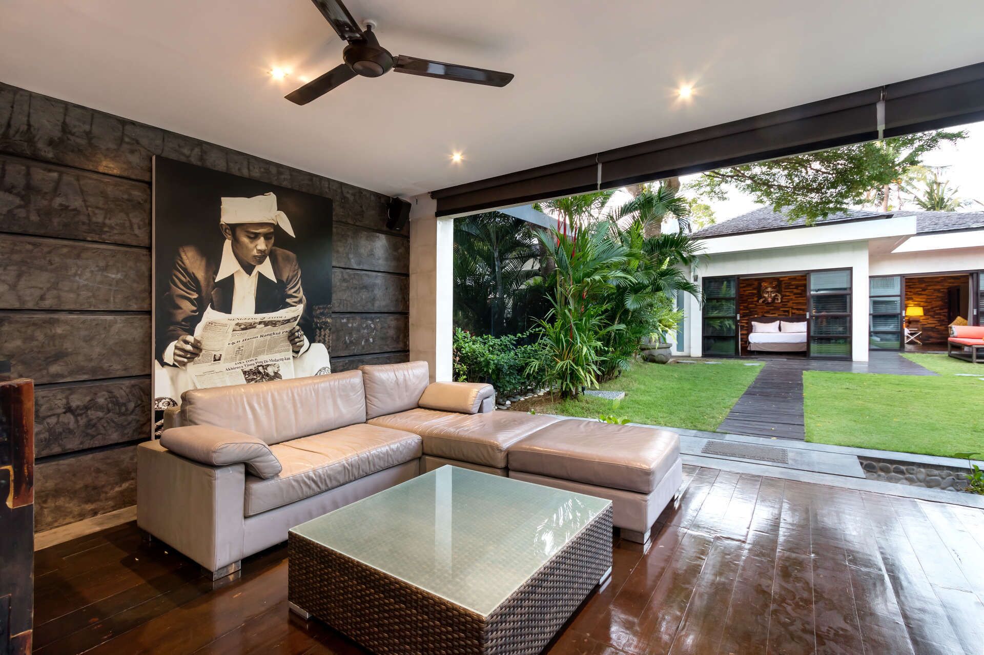 A modern living room with a sectional sofa, a glass coffee table, and a ceiling fan.