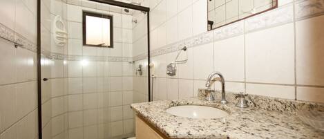 Un baño con ducha, inodoro, lavabo y espejo.