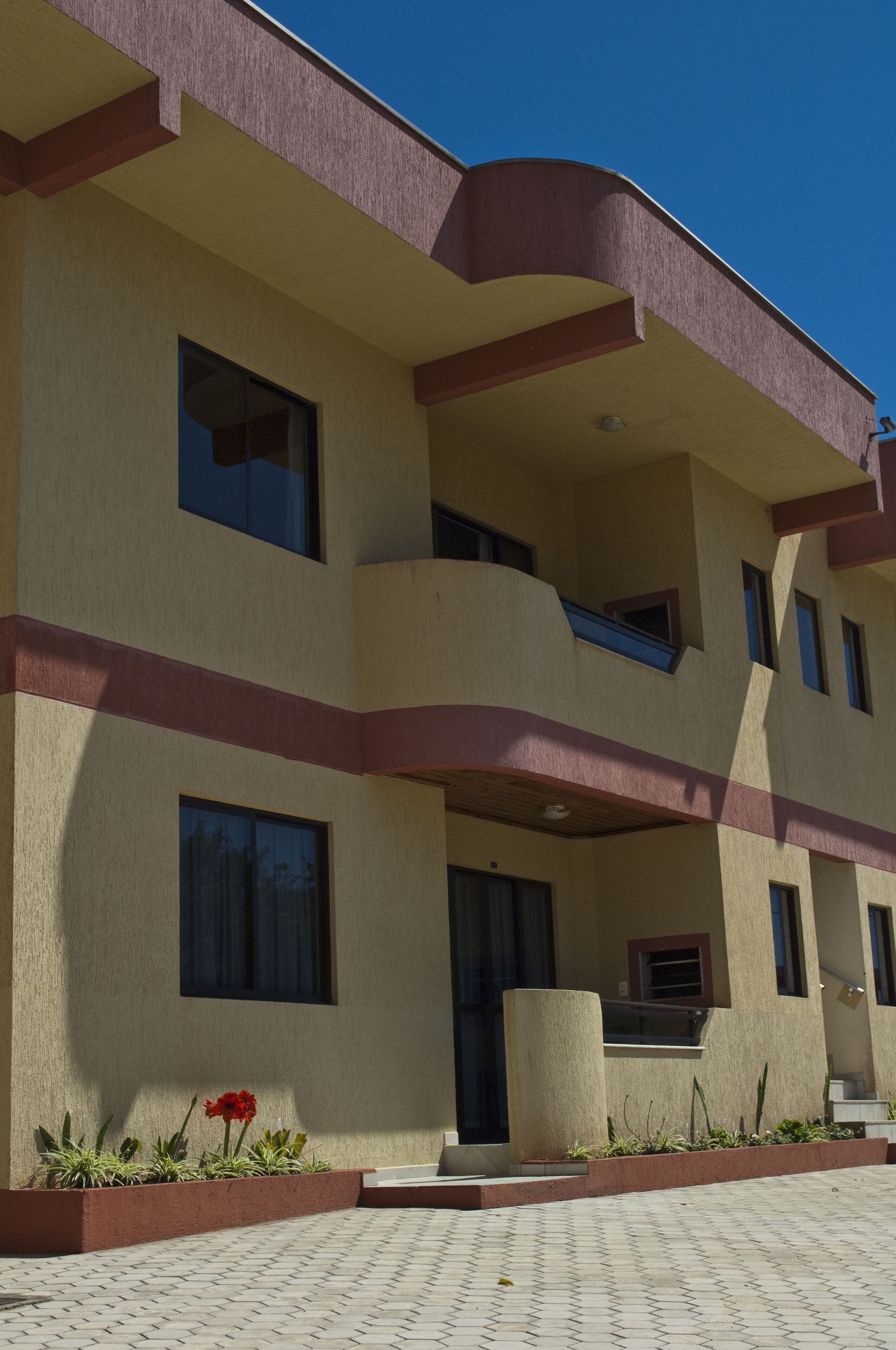 Un immeuble à plusieurs étages, doté d’une façade beige, de touches de couleur rouge et d’un balcon au deuxième étage.