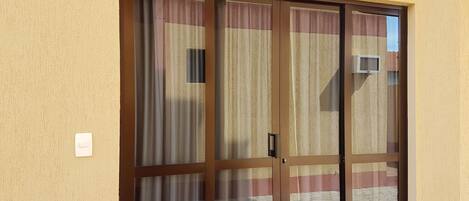 A sliding glass door with a number plate, a light fixture above it, and a power outlet on the wall.