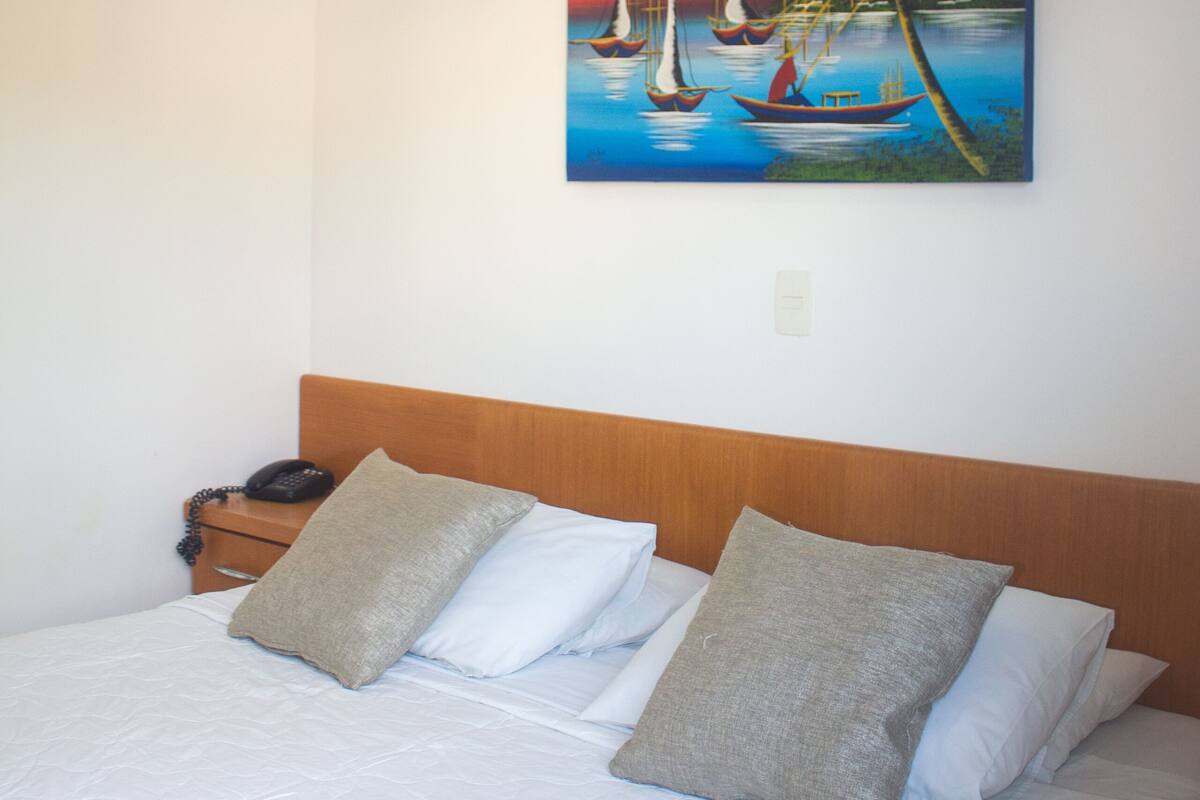 Ein Hotelzimmer mit einem Bett, einem Segelbootgemälde und einer Klimaanlage.