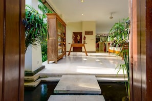 A hallway with a wooden table, a cabinet, and a bed.