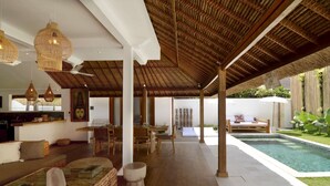 Amplio espacio interior con piscina, suelo de madera y techo de paja.
