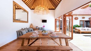 A wooden dining table with a woven centerpiece, a sofa with cushions, and a large mirror on the wall. - Beautiful 5 Star Holiday Villa in a Prime Location in Seminyak, Villa Bali 2046 (Bali)