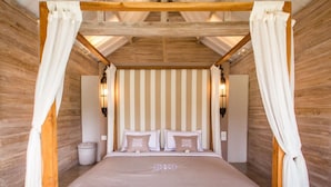 Quarto com cama de dossel, papel de parede listrado e luminárias fixadas na parede.