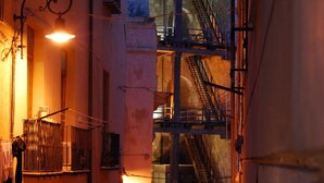 Un edificio con escaleras de emergencia, barandilla metálica y lámpara colgante.