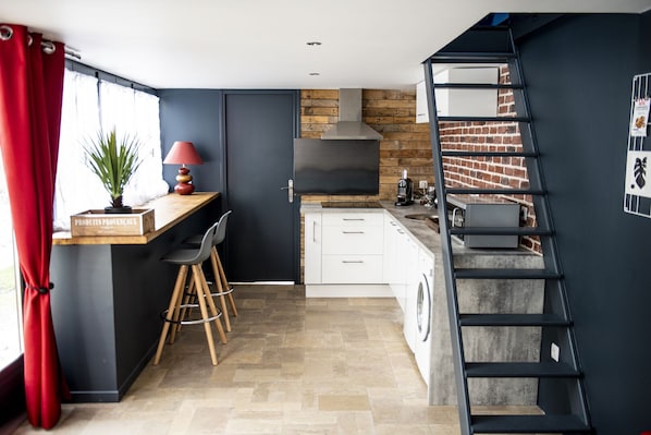 A modern kitchen with a built-in stove, a coffee machine, and a washing machine.