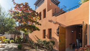 A building with a stone-paved courtyard, a wooden door, and a balcony with a railing. - Casa Bella 2BR by Casago (Loreto)