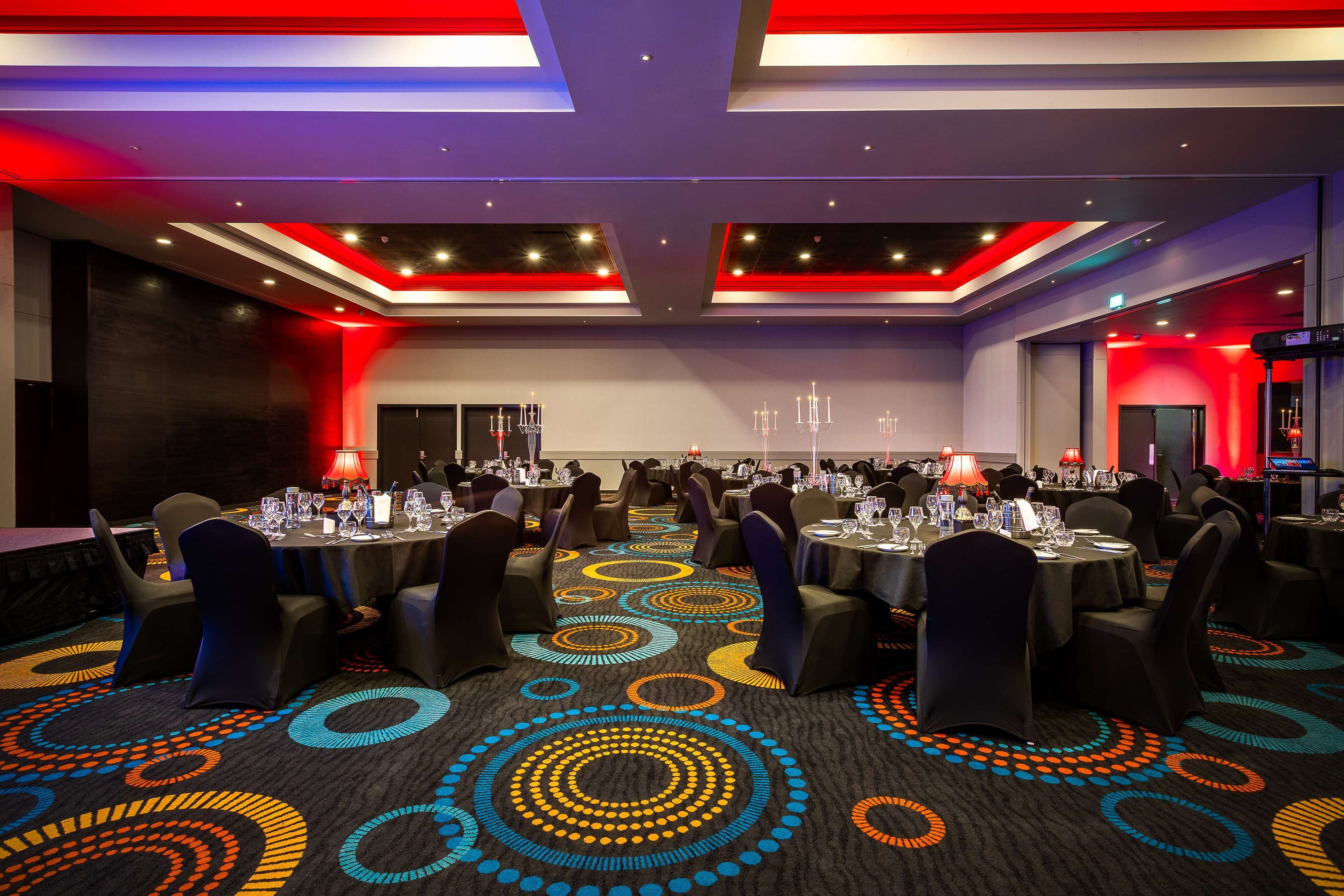 A conference room with round tables, chairs, and a patterned carpet.