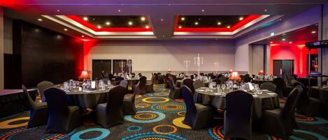 A conference room with round tables, chairs, and a patterned carpet.