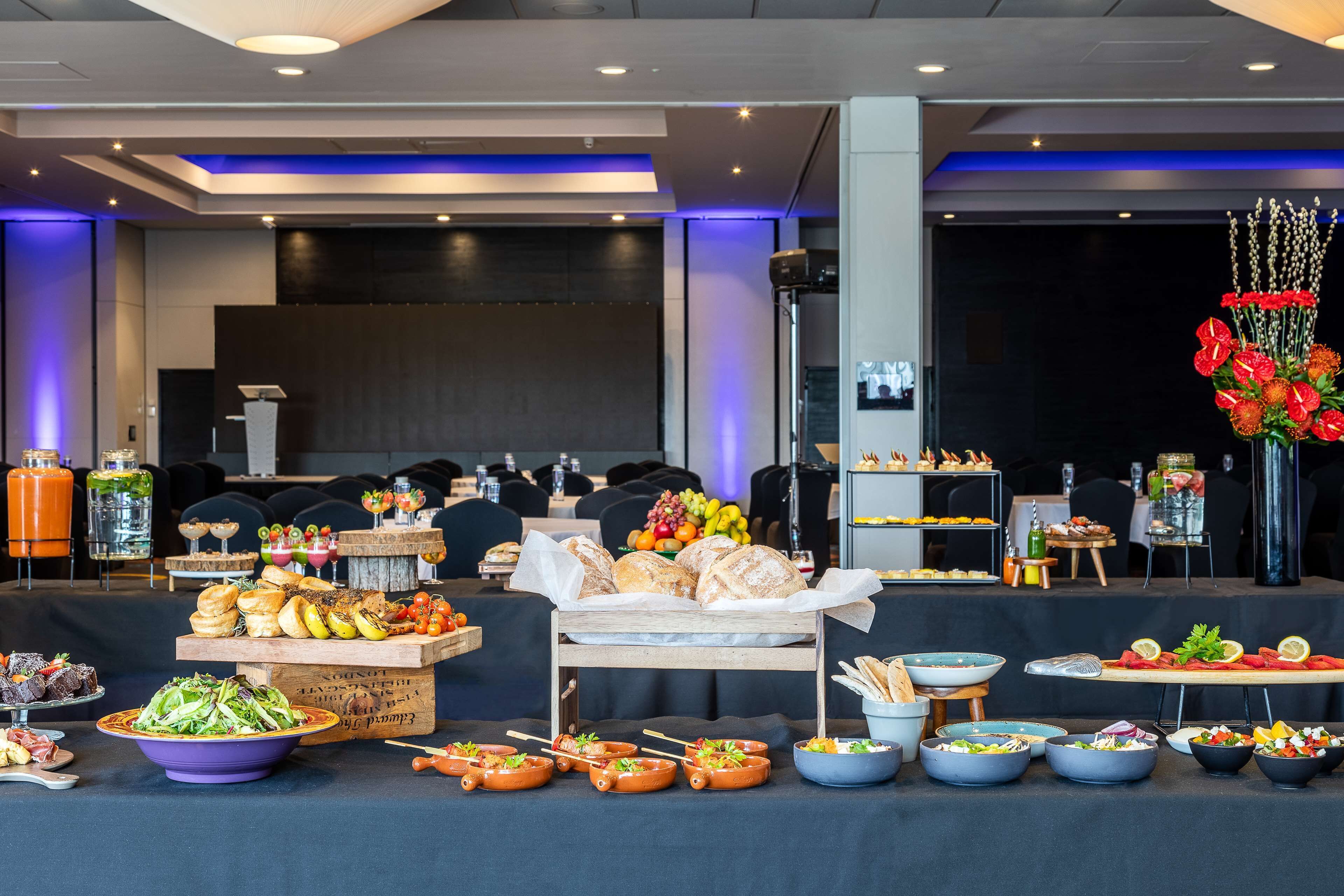 A buffet setup with various food items and a decorative flower arrangement.