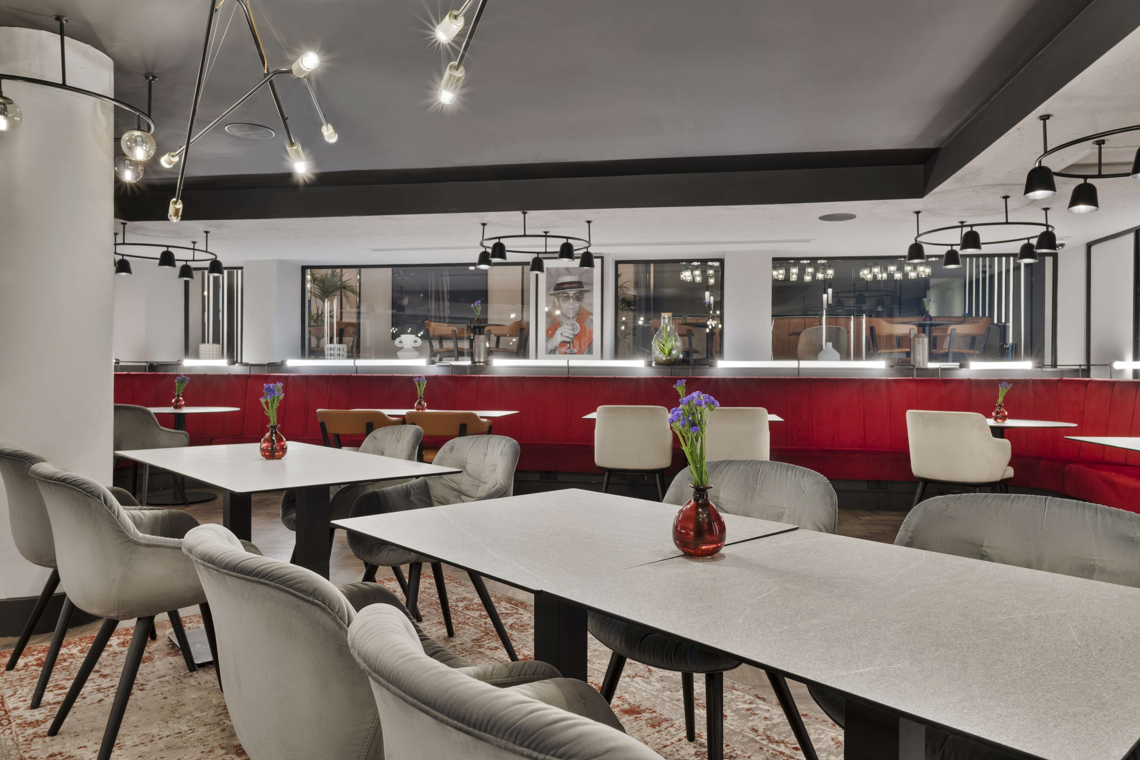 A modern restaurant with tables and chairs, a counter, and pendant lighting.