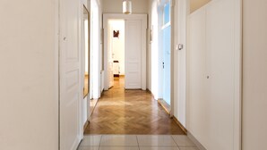 A hallway with wooden flooring, white walls, and doors leading to other rooms.