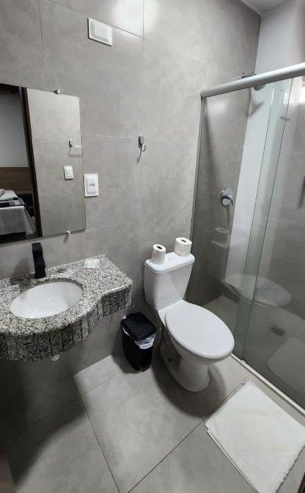 A bathroom with a granite sink, toilet, and glass shower enclosure.