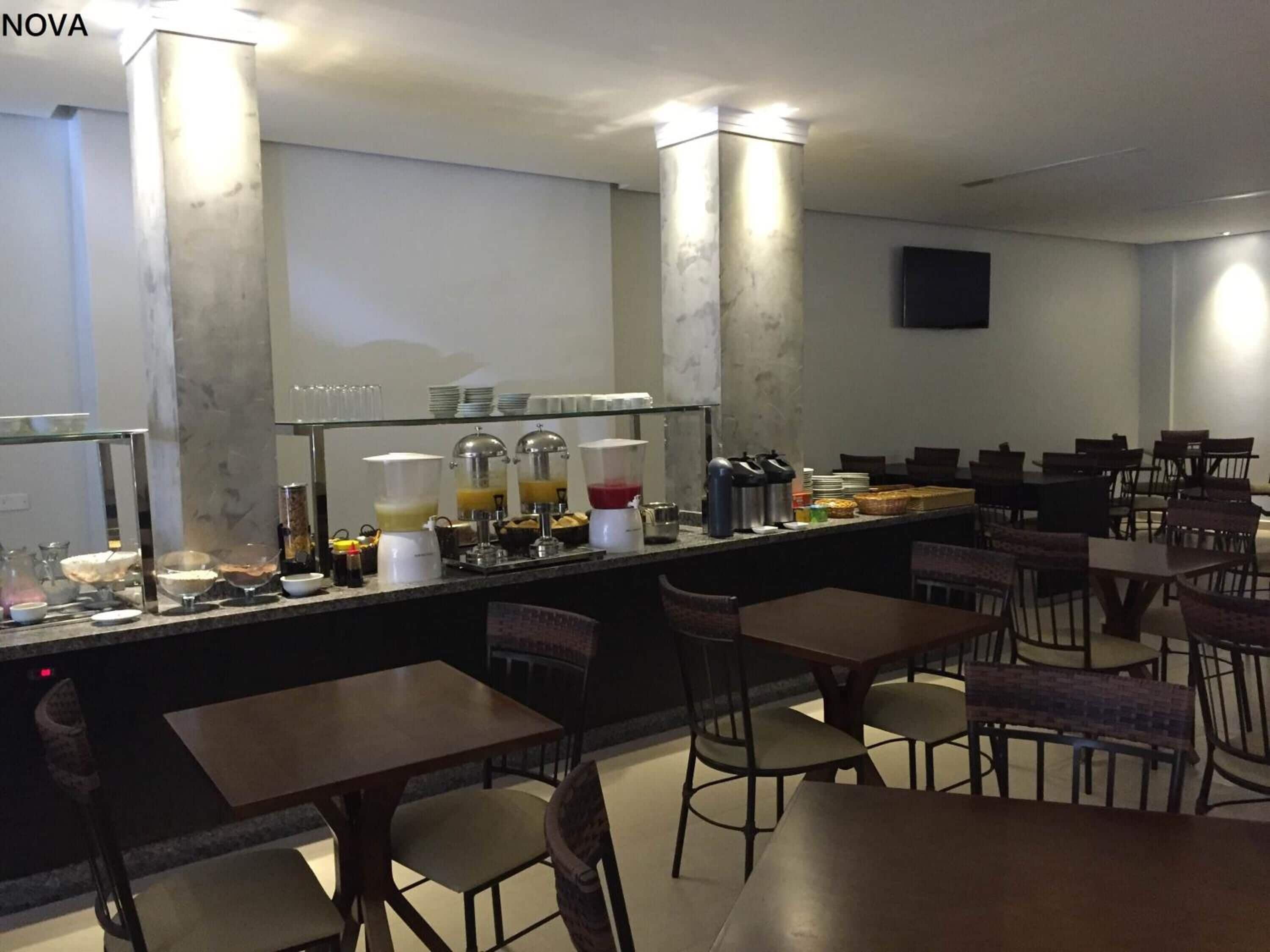 A breakfast bar with various food items and beverages, surrounded by tables and chairs.